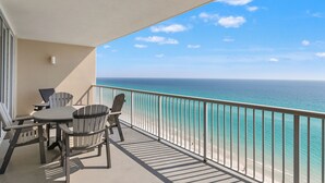 Ein Balkon mit Tisch und Stühlen mit Blick auf Strand und Meer.