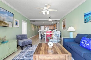 Ein Wohnzimmer mit Deckenventilator, Couchtisch, Sofa und einem Essbereich mit Stühlen und Tisch.