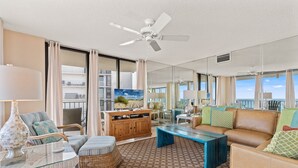 Ein geräumiges Wohnzimmer mit Deckenventilator, großem Fenster und Meerblick.