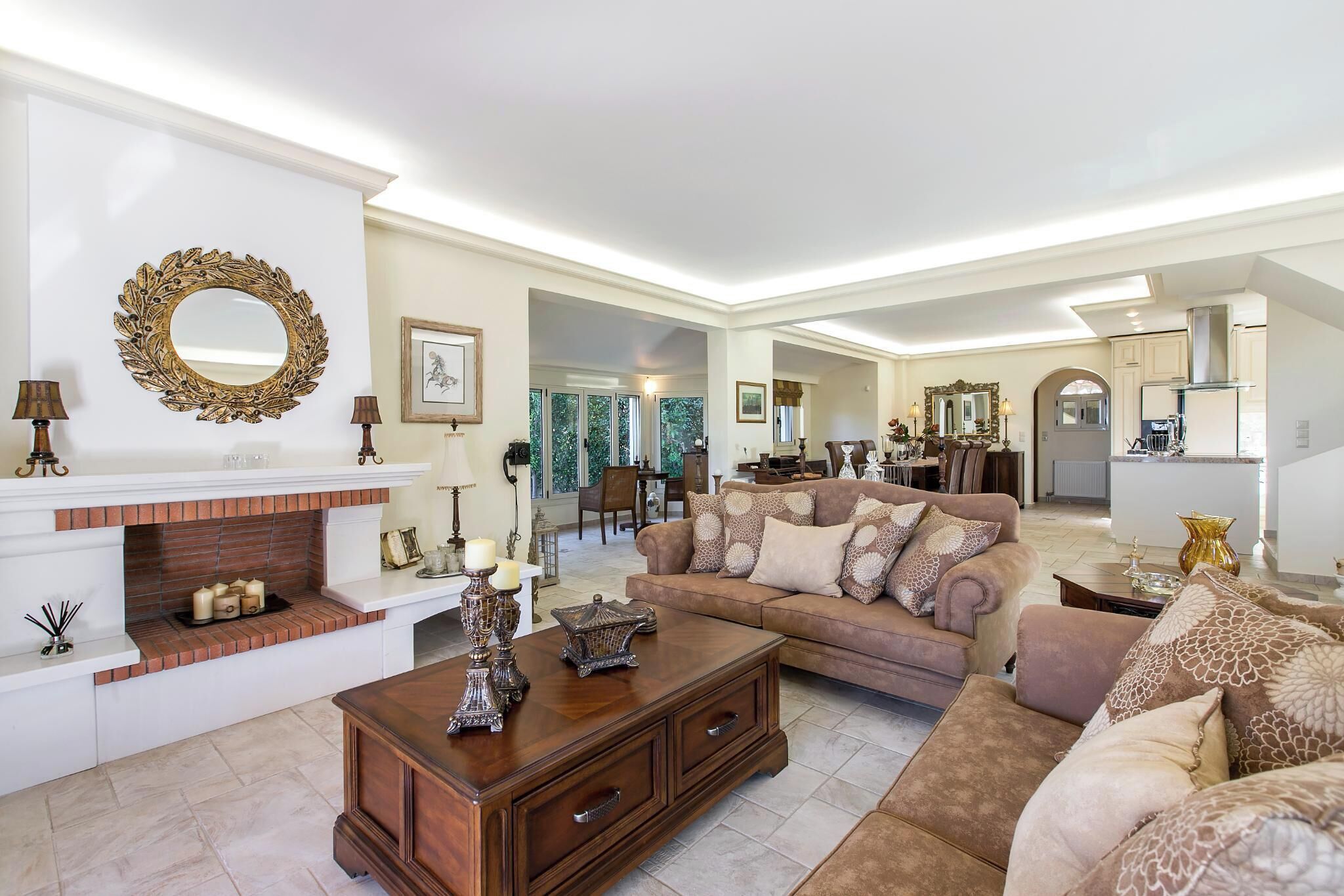 A spacious living room with a fireplace, a large sofa, and a dining area in the background.