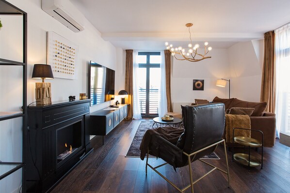 Una sala de estar moderna con chimenea, un sofá, una mesa de centro y una araña.