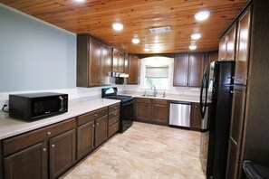 A kitchen with wooden cabinets, a microwave, stove, sink, and dishwasher. - Cute & Cozy! Close to ramps, stores & more! (Port Mansfield)