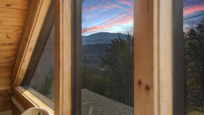 Una cabaña de madera con un amplio ventanal que da a un paisaje montañoso.