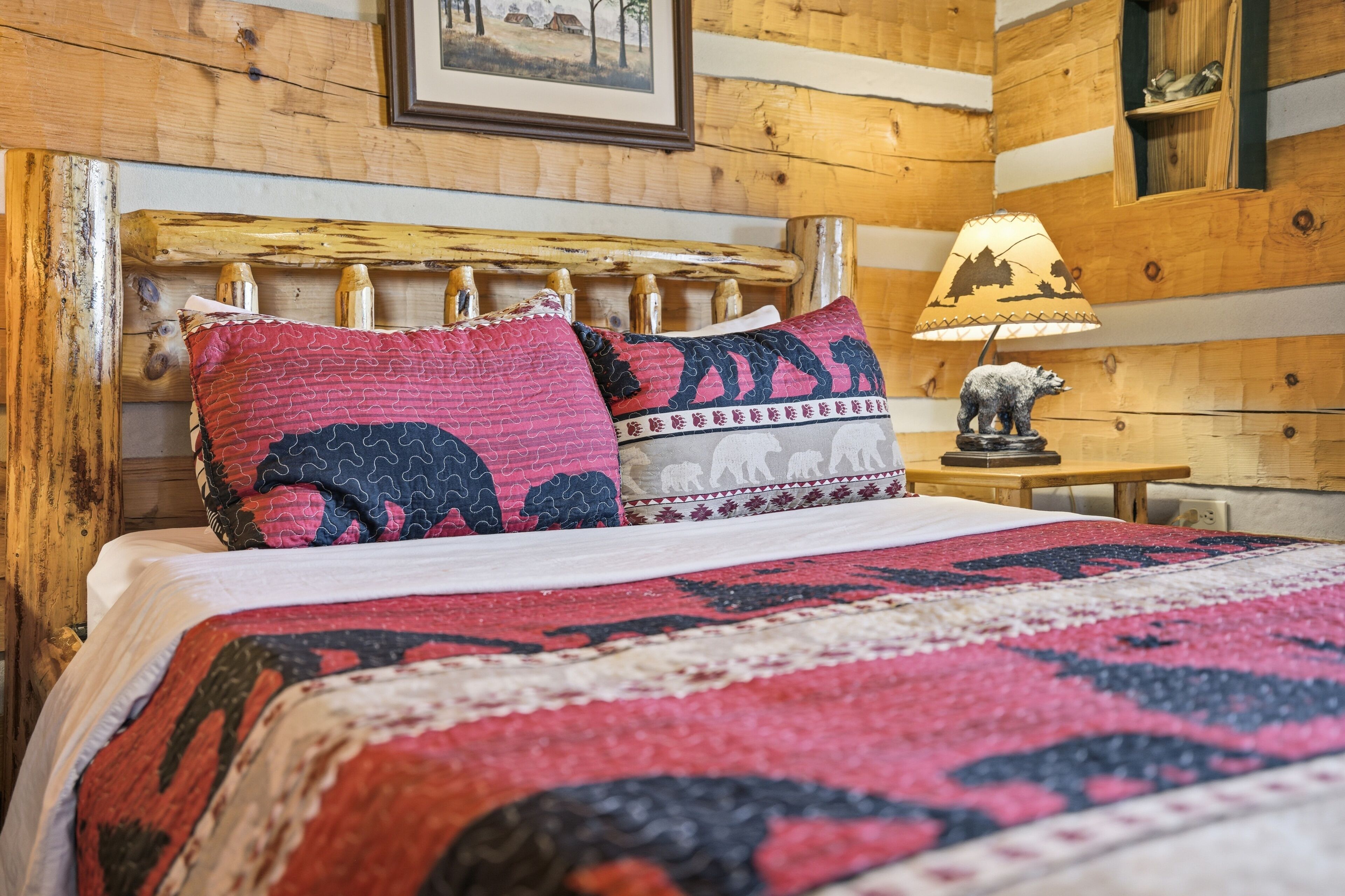 Ein holzgetäfeltes Zimmer im Blockhausstil mit einem Bett, einer Lampe und einem gerahmten Bild an der Wand.