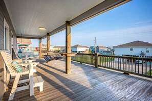A wooden deck with a covered porch, outdoor seating, and a view of neighboring houses. - Sea Worthy 3 Bedroom Home (Port Bolivar)