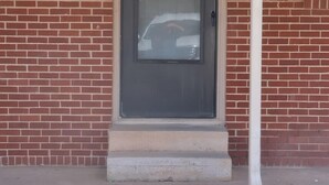 A brick building with a dark-colored door and a small porch.