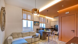 Une cuisine moderne dotée d’un îlot central, un coin repas avec une table et des chaises, et un salon avec un canapé et une table basse.