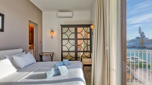 Une chambre d’hôtel avec un grand lit, un bureau, une chaise et une vue sur un navire de croisière.