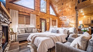 A cozy log cabin interior with a large bed, a sofa, and a dining area. - Private Luxury Retreat | Hot Tub, Fire Pit & Views (Sevierville)