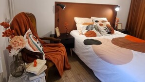 A hotel room with a bed, bedside tables, a chair, and a nightstand. - Between lakes and mountains (Cluses)