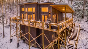 Eine Holzhütte mit einer Holzterrasse und einem überdachten Obergeschoss.
