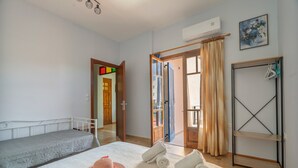 A room with a bed, a wardrobe, a hanging rack, and a door leading to another room. - Apartment 'Mati Guest House' with Sea View, Wi-Fi and Air Conditioning (Νυδρί)