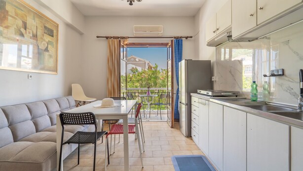 A compact kitchen with a dining area, a sofa, and a view through a doorway. - Apartment 'Mati Guest House' with Sea View, Wi-Fi and Air Conditioning (Νυδρί)