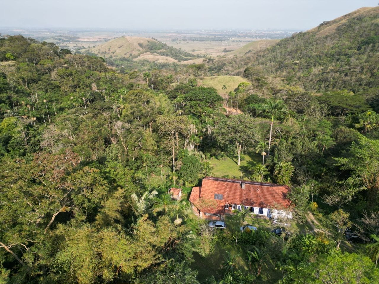 Uma casa rodeada por vegetação densa e colinas.