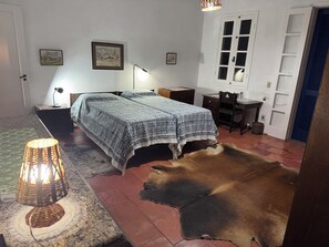 Un dormitorio con cama, mesitas de noche, escritorio y silla. Hay una alfombra y una lámpara en el suelo.