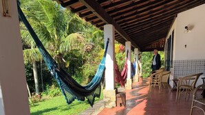 Un espace extérieur abrité, doté d’un sol carrelé, de hamacs et de meubles en osier.