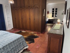 Una habitación con una cama, un armario de madera, un tapete y una lámpara.