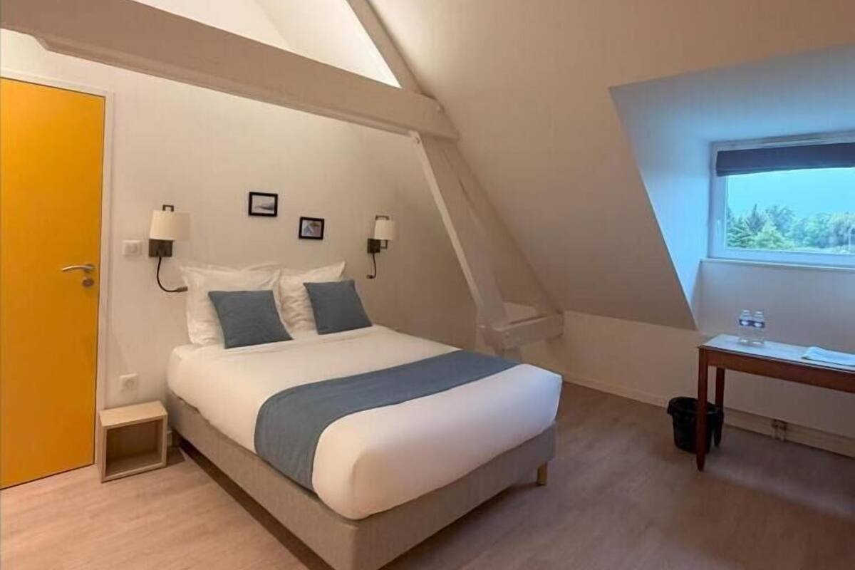 Un dormitorio con cama, escritorio y ventana.