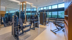 A modern gym with various exercise equipment, large windows, and a clean, well-lit interior. - Balcony Facing the Marina with Partial Sea Views, Steps from the Beach (Dubai)