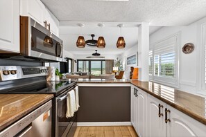 A modern kitchen with stainless steel appliances, a central island, and a view to the outdoors. - Aldea 1 Beachfront Condo in Belleair Beach (Belleair Beach)