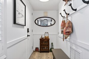 Ein Flur mit einem gerahmten Bild, einem ovalen Spiegel, einem Holzschrank und einer Wandvitrine.
