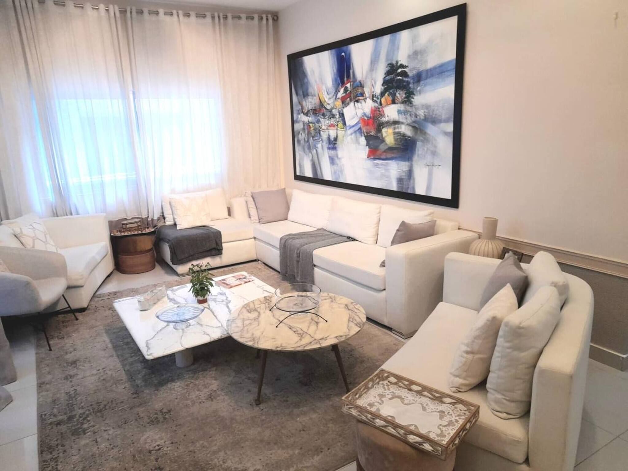 A modern living room with a sectional sofa, a coffee table, and a large abstract painting on the wall.