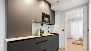 Une cuisine moderne avec des meubles de couleur sombre, un four à micro-ondes et un évier.