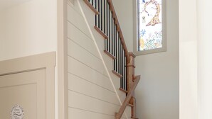 A staircase with wooden steps and a wooden handrail, leading to a door with a circular sign. - Cozy New House in a Prime Location (Carrollton)
