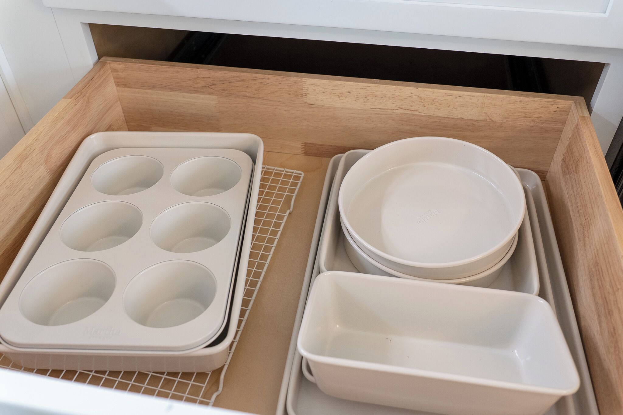 Keittiönlaatikossa on muffinipelti, metallinen ritilä ja päällekkäin asetettuja kulhoja.