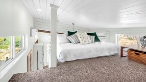 A bedroom with a large bed, a wooden headboard, a window, and a view of the outdoors. - Secluded Hill Country Ranch on 105 Acres Near Pedernales State Park (Johnson City)