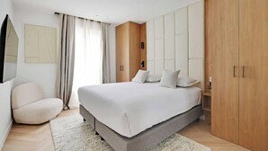 Una camera da letto moderna con un letto grande, un armadio e un angolo salotto.