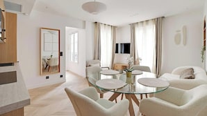 Un soggiorno moderno con un tavolo da pranzo in vetro circondato da sedie, un divano e una TV.