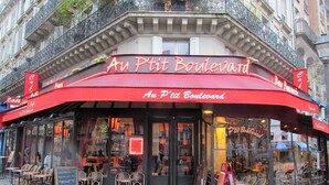 Un ristorante chiamato "Au P'tit Boulevard" con posti a sedere all'aperto e un tendone rosso.