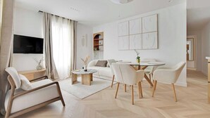 Un soggiorno moderno con divano, tavolo da pranzo, sedie, televisore e libreria.