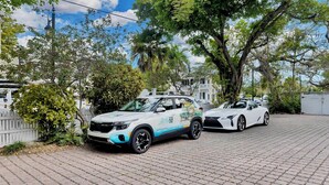 Two white cars parked on a paved driveway with trees and a white fence in the background. - **WINDWARD WAVES @ OLD TOWN** Cottage by Duval + Last Key White Glove Service... (Key West)