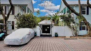 A covered car parked in front of a house with a gated entrance and a small porch. - **WINDWARD WAVES @ OLD TOWN** Cottage by Duval + Last Key White Glove Service... (Key West)