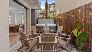 A modern outdoor patio with Adirondack chairs, a hot tub, and a bamboo wall with string lights. - Simply Paradise: Steps to Desert Color Lagoon + Beaches (St. George)