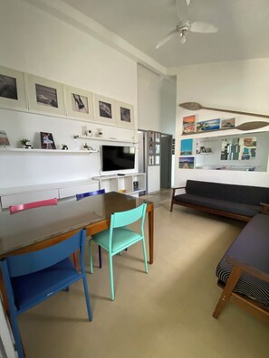 A modern living room with a dining table, chairs, a sofa, and a TV. - Beachfront house with pool next to the Sesc Cacupe hotel. (Florianópolis)