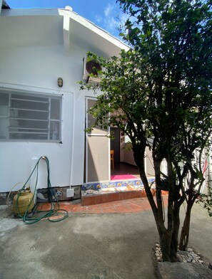 Un bâtiment blanc avec une fenêtre, une porte et un arbre devant.