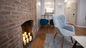 Una sala de estar moderna con chimenea de ladrillo, un comedor con sillas azules y un sillón azul claro.