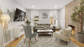 Een moderne woonkamer met een bank, twee fauteuils, een salontafel en een open haard.