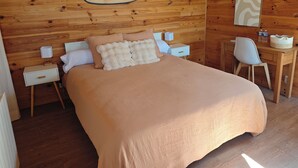 A wooden cabin bedroom with a bed, bedside tables, a desk, and a chair. - LE CHALET DES PINS (Clermont)