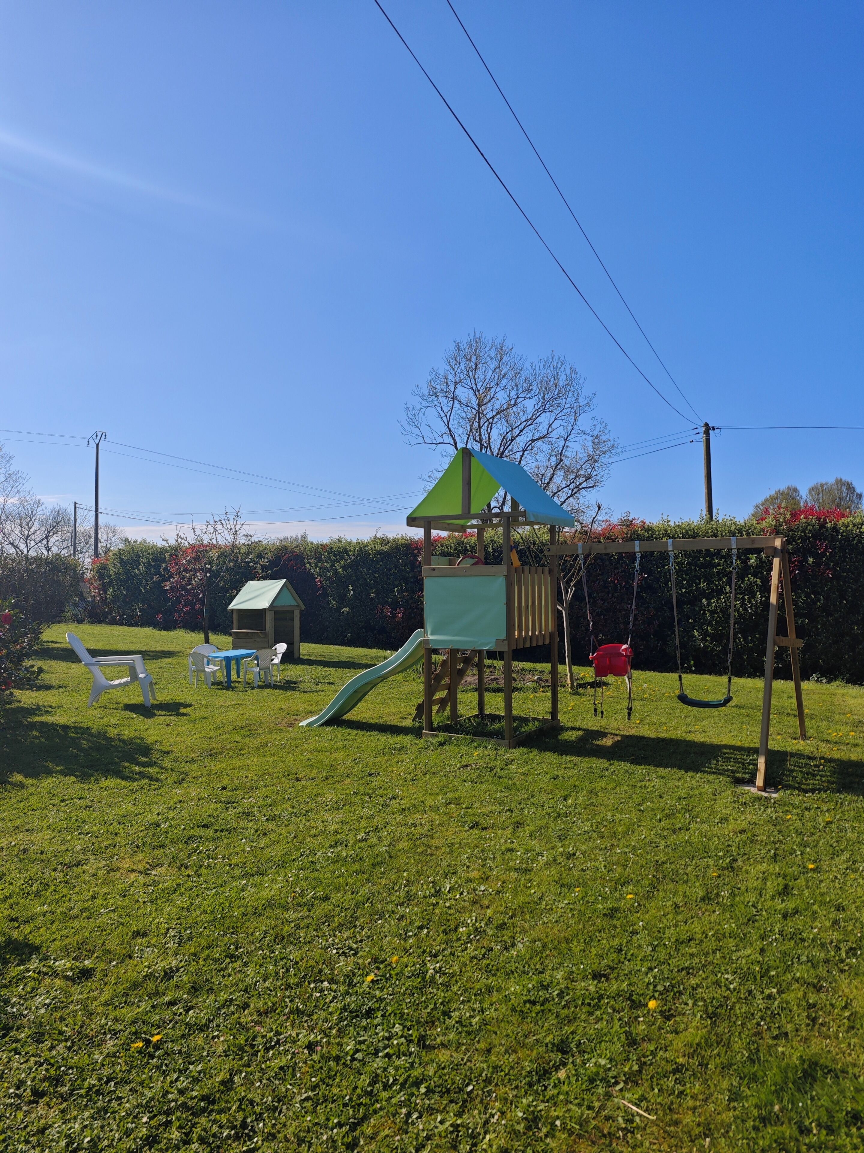 A playground with a slide, swings, and a small house structure.