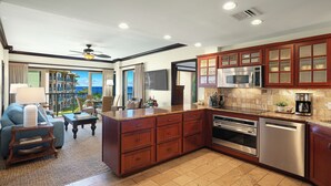 A modern kitchen with granite countertops, stainless steel appliances, and wooden cabinetry. - Waipouli Beach Resort Exquisite Ocean & Pool View - Kauai Luxury with 2 Kings (Kapaa)