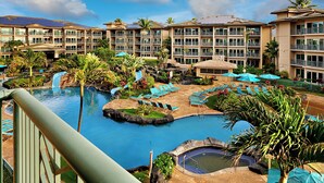 A resort with a central pool, lounge areas, and multiple-story buildings with balconies. - Waipouli Beach Resort Exquisite Ocean & Pool View - Kauai Luxury with 2 Kings (Kapaa)