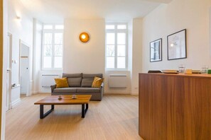 Un salon moderne avec un canapé, une table basse et un comptoir d’accueil en bois.