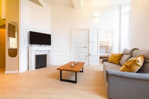 Una sala de estar con chimenea, televisor de pantalla plana, sofá y una mesa de centro.