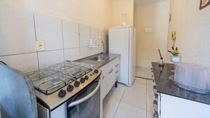 Eine kompakte Küche mit Gasherd, Backofen, weißem Kühlschrank und einer kleinen Spüle.