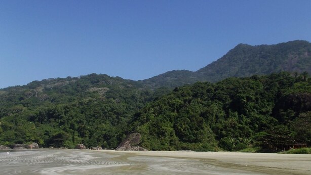Ein Strand mit einem Berg im Hintergrund.