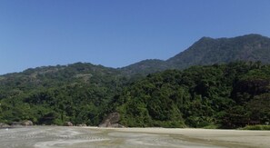 A beach with a mountain in the background. - Apartamento com Wifi e Garagem no Jardim Itatins (Peruíbe)